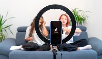 El auge de los creadores de contenido en TikTok Teléfono grabando un video de TikTok frente a dos jóvenes