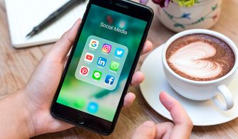 Gestión de redes sociales para marcas Smartphone con aplicaciones de redes sociales junto a una taza de café