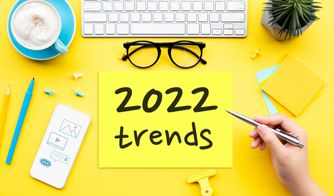 Principales tendencias de marketing digital en 2022 Mesa amarilla con taza de café, gafas y cartel que dice 2022 trends