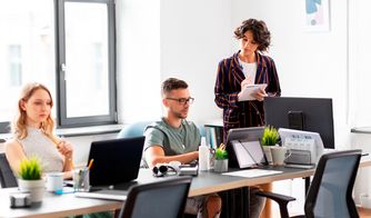 Trabajo en equipo dentro de una agencia digital Personas trabajando en una oficina moderna con computadoras y plantas
